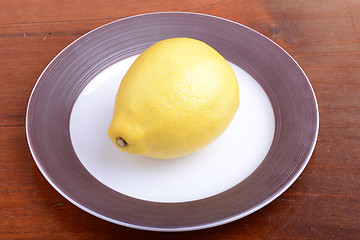 Image showing Whole lemon on a grey plate on wooden background