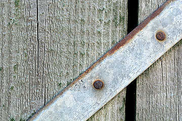 Image showing Closeup head of big metal screw on wooden plate