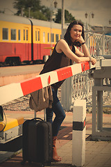 Image showing woman traveler with a suitcase near the railway barrier