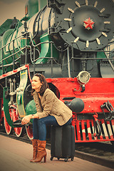 Image showing pretty woman sitting on a suitcase on railroad station