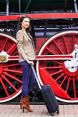 Image showing woman with a suitcase near the huge locomotive wheels