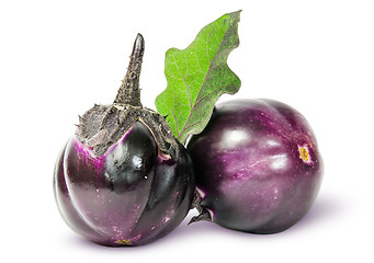 Image showing Two round ripe eggplant with green leaf