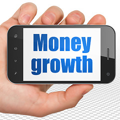 Image showing Money concept: Hand Holding Smartphone with Money Growth on display