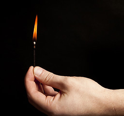 Image showing Hand holding burning match stick