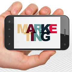 Image showing Marketing concept: Hand Holding Smartphone with Marketing on  display