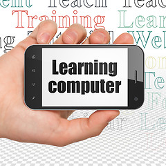 Image showing Studying concept: Hand Holding Smartphone with Learning Computer on display