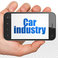 Image showing Manufacuring concept: Hand Holding Smartphone with Car Industry on display