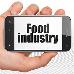 Image showing Manufacuring concept: Hand Holding Smartphone with Food Industry on display