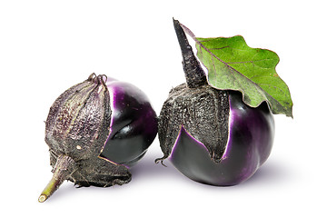 Image showing Two round ripe eggplant with green leaf rotated