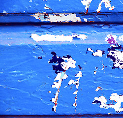 Image showing stripped paint in the blue wood door and rusty nail