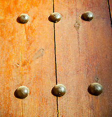 Image showing nail dirty stripped paint in the brown wood door and rusty yello