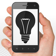 Image showing Business concept: Hand Holding Smartphone with Light Bulb on display