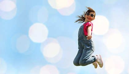 Image showing happy little girl jumping high over blue lights