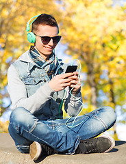 Image showing happy young man in headphones with smartphone