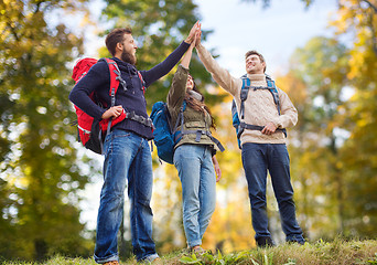 Image showing happy friends with backpacks making high five