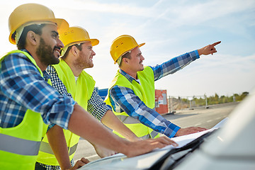 Image showing close up of builders with blueprint on car hood