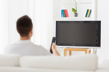 Image showing man watching tv and changing channels at home