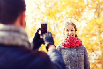 Image showing smiling couple with smartphone in autumn park