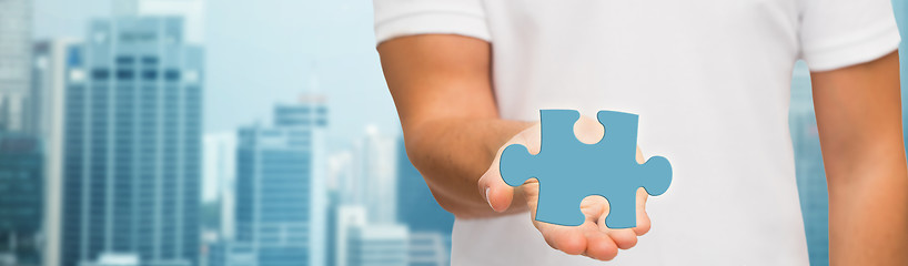 Image showing man holding blue puzzle piece over city background