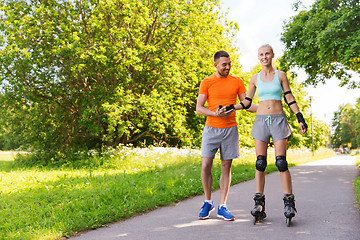 Image showing happy couple with roller skates riding outdoors