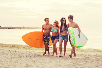 Image showing smiling friends in sunglasses with surfs on beach