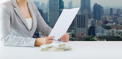 Image showing close up of female hands with money and tax report