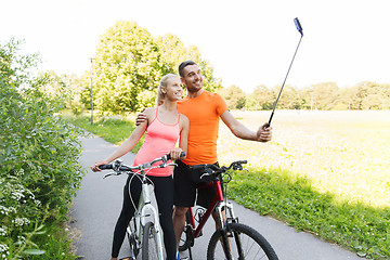 Image showing couple with bicycle and smartphone selfie stick