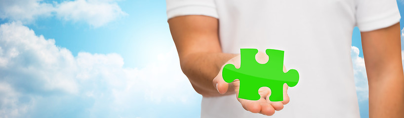 Image showing man holding green puzzle over sky background