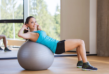 Image showing smiling woman with fit ball flexing muscles in gym