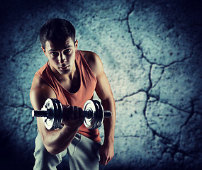 Image showing young man with dumbbell flexing biceps