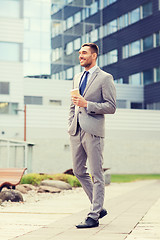 Image showing young serious businessman with paper cup outdoors