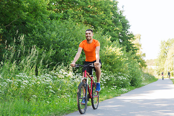 Image showing happy young man riding bicycle outdoors