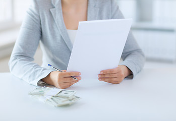 Image showing close up of female hands with money and tax report