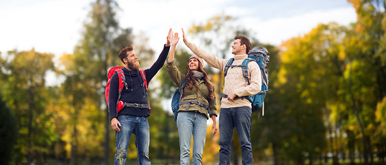 Image showing happy friends with backpacks making high five