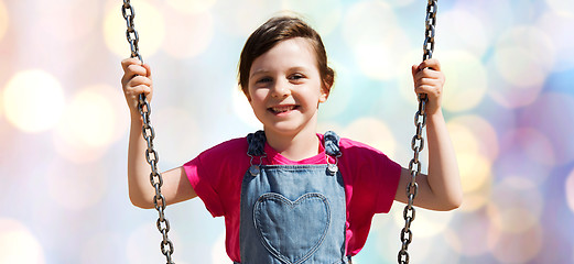 Image showing happy little girl swinging on swing over lights