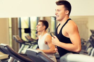 Image showing smiling men exercising on treadmill in gym