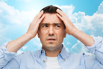 Image showing unhappy man with closed eyes touching his forehead