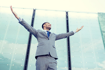 Image showing young smiling businessman over office building