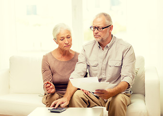 Image showing senior couple with papers and calculator at home