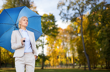 Image showing businesswoman with umbrella over autumn background