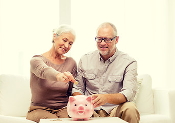 Image showing senior couple with money and piggy bank at home