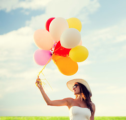 Image showing smiling young woman in sunglasses with balloons