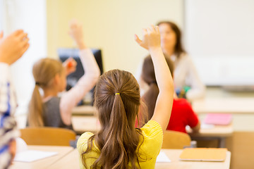 Image showing group of school kids raising hands in classroom