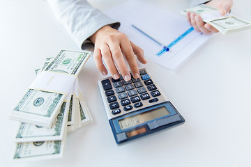 Image showing close up of hands counting money with calculator