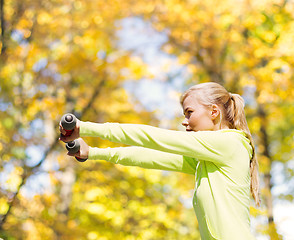 Image showing sporty woman with light dumbbells outdoors