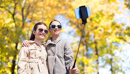 Image showing happy girls with smartphone selfie stick