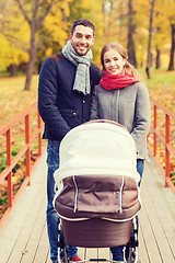 Image showing smiling couple with baby pram in autumn park