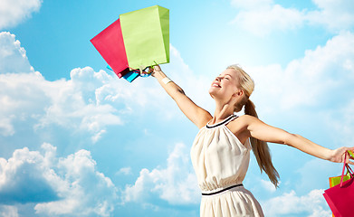 Image showing smiling woman with shopping bag rising hands