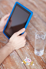 Image showing close up of hands with tablet pc, pills and water