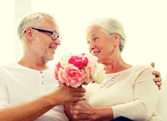 Image showing happy senior couple with bunch of flowers at home